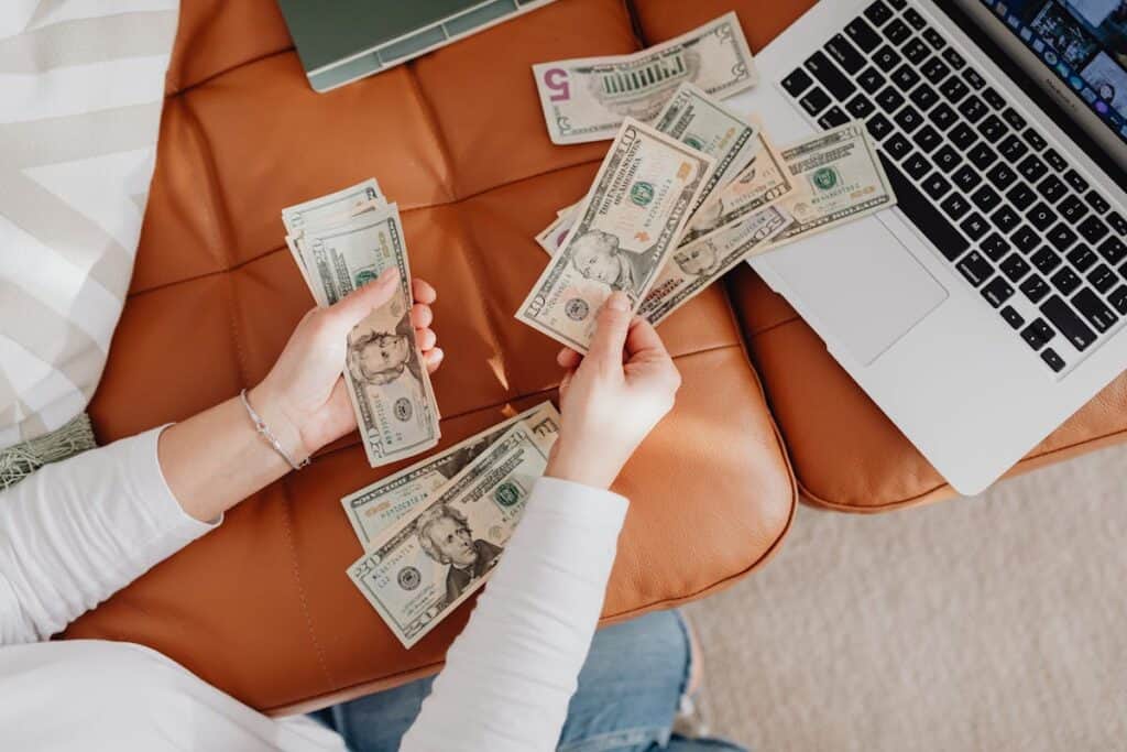 woman counting money with laptop nearby